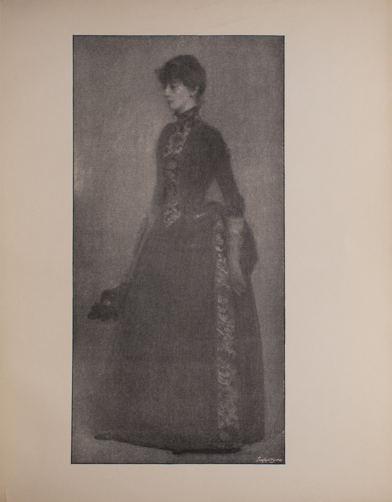 The image is of a woman standing and turned to the left She is wearing a dark coloured dress with a panel of pattern running vertically along the front of the bodice and the side of the skirt of the dress The image is vertically displayed