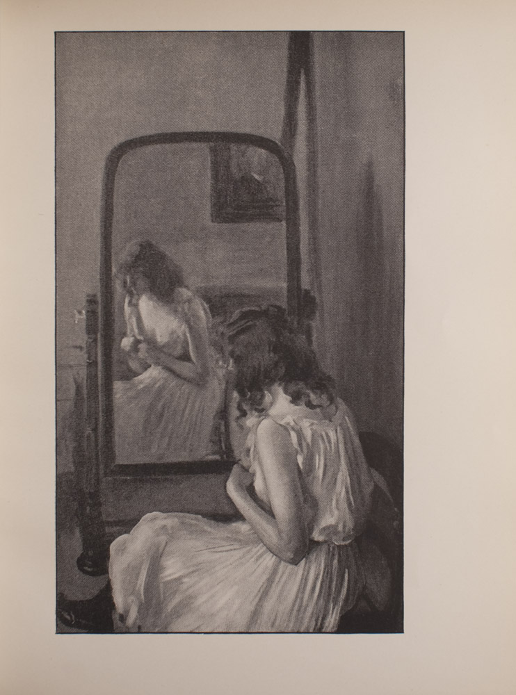 The image is of a female figure who is seated in front of a freestanding mirror Her back is to the viewer but her face is visible through the reflection in the mirror The woman is wearing a sleeveless white dressing gown with a ruffled neckline and black stockings and shoes Her hands rest together in front of her chest and her gaze is cast downwards In the mirrors reflection there is a painting that hangs on the wall behind the woman The image is vertically displayed