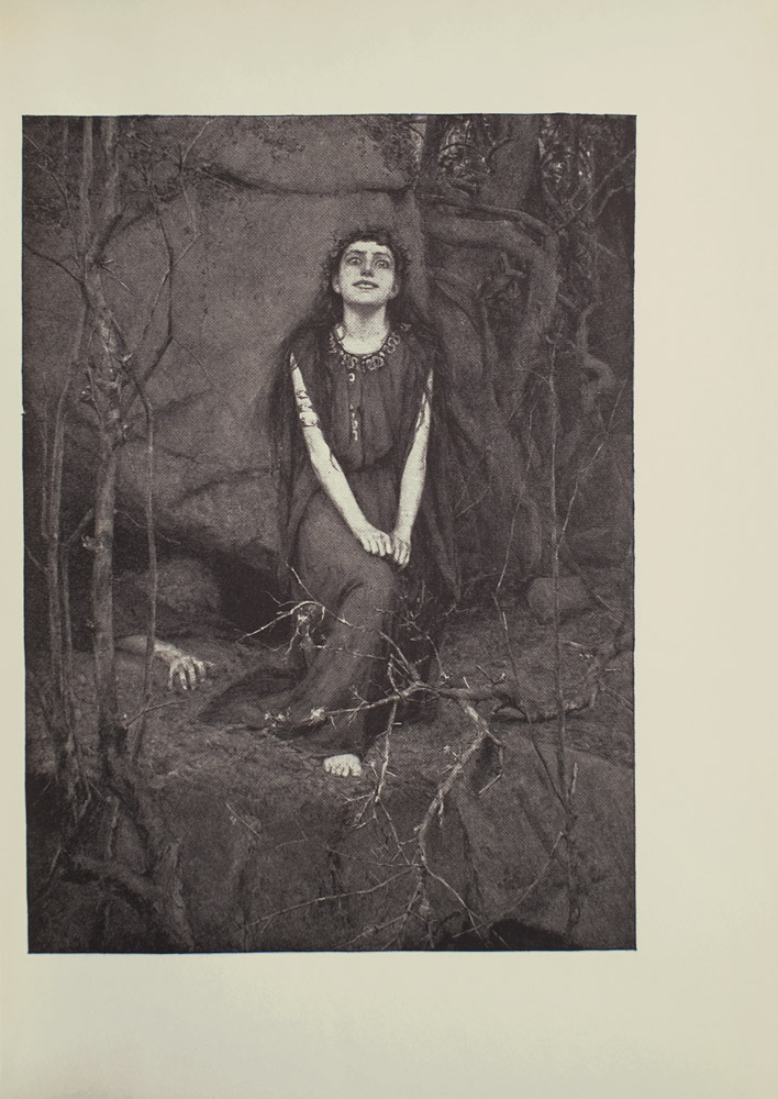Image is of a woman in a forest She is sitting in the centre of the image her face looking forward Her hands are curled up and resting on her right knee which extends away from her body A crown of leaves is sitting atop the womans long dark hair She is wearing a long sleeveless dark coloured dress with a decorated neckline The top of her right foot is poking out from beneath the dress slightly more than the toes are all that is visible A wraparound golden armlet is around her right upper arm She is shown in full face tilted slightly upward with wide almost demented eyes and a mysterious smile She is sitting in front of a large rock A persons arm is emerging from under the rock their fingers grasping at the ground The figures body is faint seen in the darkness of a large crevice Large roots and small trees branches surround the image The image is vertically displayed
