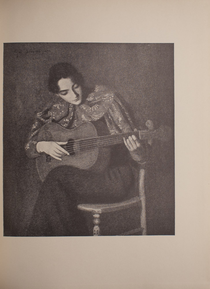 The image is of a seated woman playing an acoustic guitar The woman has dark hair and her gaze is cast downwards and to the right towards the guitar in her lap Her left hand is on the fret board while her right hand plucks the strings She is wearing a patterned top with a large collar and appears to be sitting with her legs crossed The image is vertically displayed