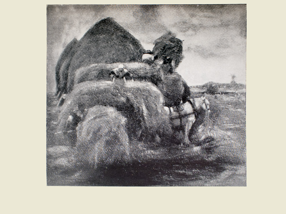 Image is of a woman stacking hay onto a wagon She the horse and the wagon are in the middle ground The horse is white and is shown in profile facing the right of the image The woman is wearing a light coloured bonnet Behind the woman is a larger stack of hay a figure shown from the back is on top of it In behind this larger stack are three buildings with straw roofs The sky is light coloured The image is horizontally displayed