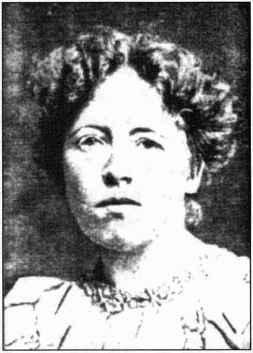 Black-and-white headshot of Alice Woodward. She is facing and gazing at the viewer. She is wearing a light-coloured, high-necked outfit and her hair is loosely gathered at the back of her head.